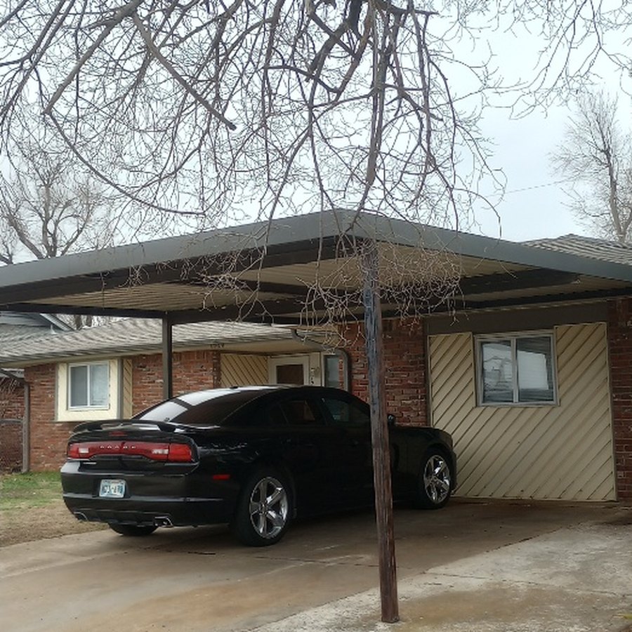 Heavy dead branches drooping low over the same carport before removal